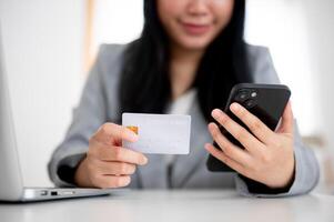 A businesswoman is holding a smartphone and a credit card, using online payment banking. photo