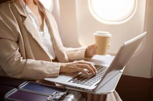 A cropped image of a hard-working businesswoman is working on her laptop during the flight. photo