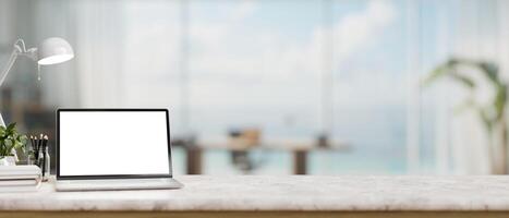 un blanco mármol mesa con un ordenador portátil computadora Bosquejo y accesorios en un moderno hogar oficina. foto