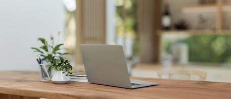 A laptop computer on a wooden dining table in a neutral contemporary dining room or kitchen. photo