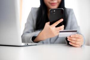 A businesswoman is holding a smartphone and a credit card, using online payment banking. photo