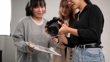 A photographer is showing images on her camera to art directors, working with her team in the studio photo