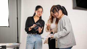 un hembra fotógrafo es hablando y demostración imágenes en el cámara a su equipo, trabajando en el estudio foto