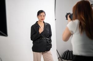 An attractive young Asian female model is posing for a photographer, taking a photoshoot in a studio photo