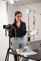un Frío, atractivo asiático hembra fotógrafo productor es trabajando en un disparo estudio. foto