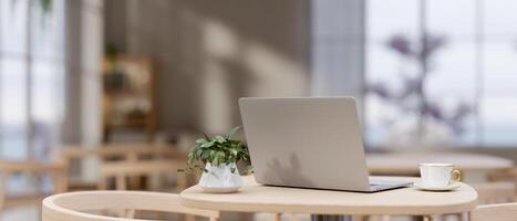 A back view image of a laptop computer on a wooden table in a modern cozy neutral coffee shop. photo