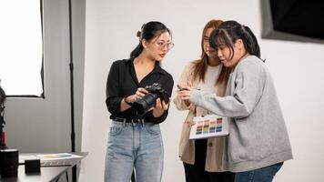 A female photographer is talking and showing images on the camera to her team, working in the studio photo