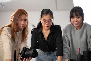 un profesional asiático hembra fotógrafo es trabajando con su asistentes en un Sesión de fotos estudio.