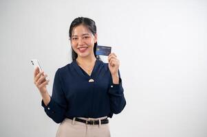 un atractivo asiático mujer es demostración un crédito tarjeta a el cámara, estudio antecedentes. en línea pago foto