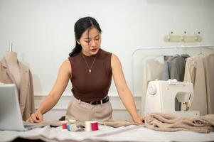 un profesional asiático hembra Moda diseñador o Sastre es enfoque en su trabajo en el taller estudio foto