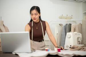 A professional, confident Asian female fashion designer is working in her studio. photo