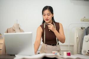 A professional, confident Asian female fashion designer is working in her studio. photo