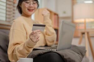 un mujer es registrando su crédito tarjeta en un compras sitio web, disfrutando compras en línea a hogar. foto