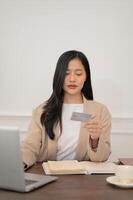 un atractivo asiático mujer de negocios es registrando su crédito tarjeta en el sitio web foto
