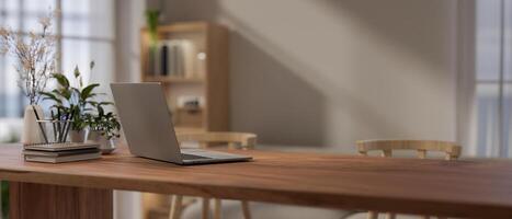 A close-up image of a laptop and accessories on a wooden table in a cosy, Scandinavian room. photo