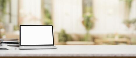 A laptop computer mockup on a table with a blurred background of a contemporary coffee shop. photo