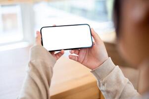 A white-screen smartphone mockup in a horizontal position in a woman's hand. photo