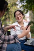 A cheerful Asian woman is enjoying talking with her friend while sitting in a backyard together. photo