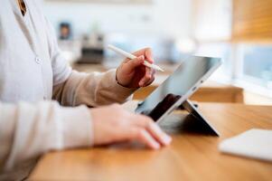 A side view image of a woman working remotely at a cafe, using her digital tablet. photo