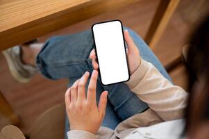 A close-up image of a woman using her smartphone at a table in a cosy cafe. photo