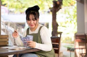 Happy Asian female small business owner is satisfied with her revenue, managing her shop's finances. photo