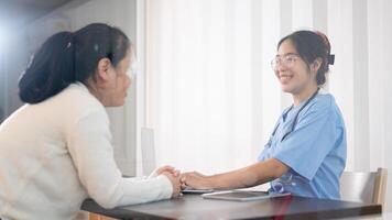 un profesional asiático hembra médico es consultante un hembra paciente en el oficina a el hospital. foto