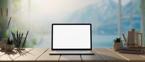 A laptop computer mockup on a wooden tabletop with a blurred background of snowy mountains. photo