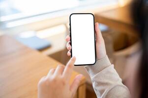 A close-up image of a woman using her smartphone at a table in a cosy cafe. photo