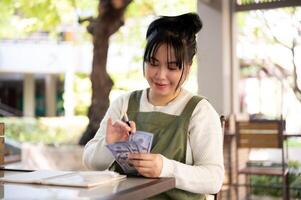 Happy Asian female small business owner is satisfied with her revenue, managing her shop's finances. photo