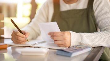 A female small business owner calculating her monthly expenses, checking bills receipts. photo