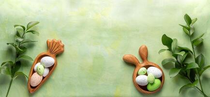 Wooden plates as bunny and carrot with Easter eggs, green Ruskus twigs on green yellow Copy space photo