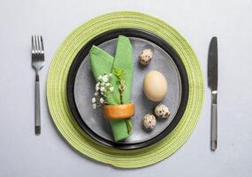 Natural Easter table. Gray plates, green napkins, organic eggs, cutlery, spring twig, gypsophila. photo