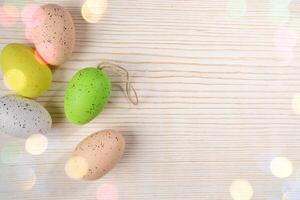 Easter card template. Decorative spotted pastel color Easter eggs on white wood with bokeh lights. photo