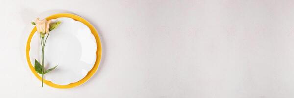Elegant table setting banner with peach Eustoma flower on empty plates. Top view. Copy space. photo