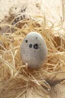 One quail egg standing on straw close up. Beauty in nature on Easter card. Vertical format. photo