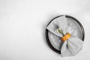 Table serving in gray tones. Gray napkin on stylish plates on gray background. Top view. Copy space. photo