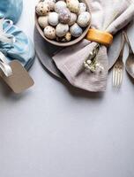elegante gris Pascua de Resurrección mesa ajuste. codorniz huevos, servilleta , Clásico cuchillería. parte superior vista. vertical formato. foto