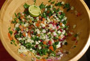 A salad with pomegranate, red onion, apple, cucumber, parsley, tomatoes and lime photo