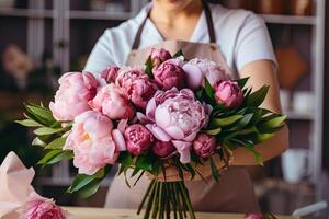 Woman creatively arranging pink hybrid tea roses in a vase photo