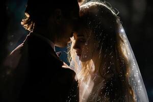 Wedding of a man and a woman. They hug and pose for a photo. Warm colors, dark background. Mysterious atmosphere photo