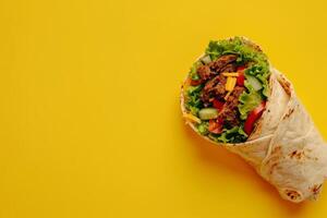 Large meat shawarma on a yellow background. Copy space photo