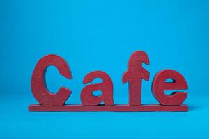 Español café palabra tallado en madera aislado en azul antecedentes. foto