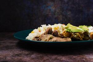 Mixed food on a plate in the foreground. Rice, tacos, steaks. photo