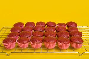 Freshly baked red velvet cupcakes cooling on a yellow background. photo