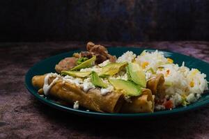 Mixed food on a plate in the foreground. Rice, tacos, steaks. photo