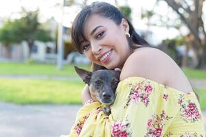 mujer abrazando su mascota en un público jardín a puesta de sol. perro amante. foto