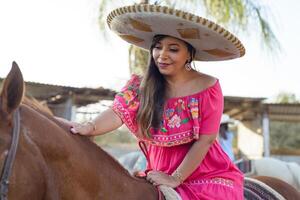 mexicano mujer vistiendo tradicional vestir y charro sombrero en lado de caballo. cinco Delaware mayonesa celebracion. foto