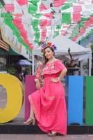 mexicano mujer vistiendo tradicional disfraz siguiente a el gigante letras de el ciudad de colima. cinco Delaware mayonesa celebracion. foto