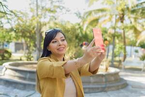 Woman in a public park taking a selfie. Sunny day. photo