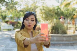 Woman in a public park taking a selfie. Sunny day. photo